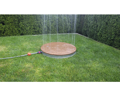 Okrúhly zavlažovač trávnika z dreva a kovu na trávniku v záhrade.