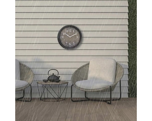 Scéna s nástennými hodinami, dvoma stoličkami a stolom vonku v daždi.