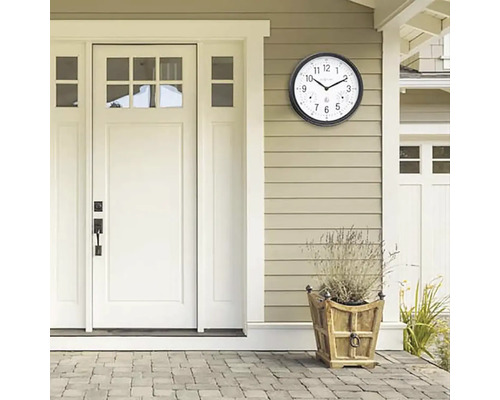 Scéna s vonkajšími hodinami s teplomerom na stene domu vedľa dverí a kvetináča.