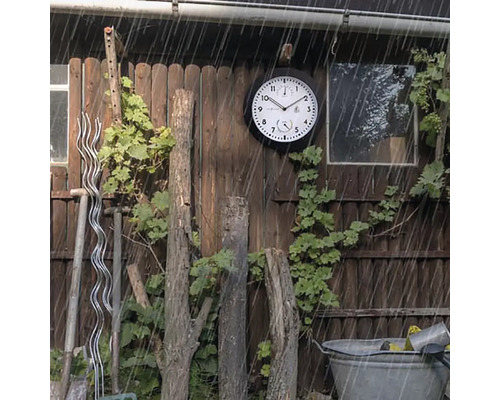 Záhradná scéna s vonkajšími hodinami odolnými voči poveternostným vplyvom na drevenej stene v daždi.