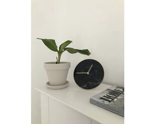 Stolová dekorácia s izbovou rastlinou v kvetináči, okrúhlymi hodinami a knihou