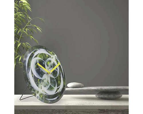 Stolové hodiny s abstraktným kvetinovým vzorom a žltými ručičkami na stole