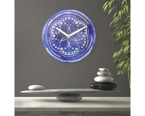 Dekoratívne nástenné hodiny s mandalovým vzorom nad hromadou kameňov