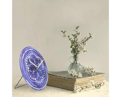 Stolové hodiny so vzorom vedľa kvetov a knihy