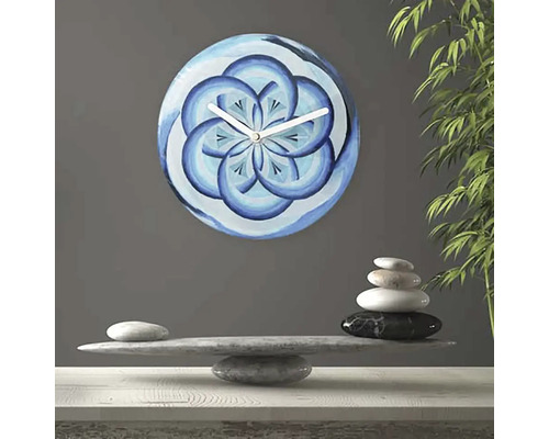 Nástenné hodiny s modrým kvetinovým vzorom vedľa kamennej rovnováhy