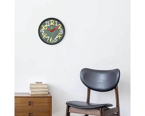 Nástenné hodiny s ciferníkom a číslicami nad drevenou skrinkou a stoličkou