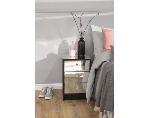 Nočný stolík s tromi zásuvkami, zrkadlovými čelami a krištáľovými úchytkami v spálni vedľa postele.