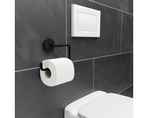 Kovový držiak toaletného papiera s rolkou toaletného papiera vedľa splachovača toalety