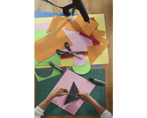 Remeselná scéna s papierom, nožnicami, lepiacou pištoľou a rezacou podložkou