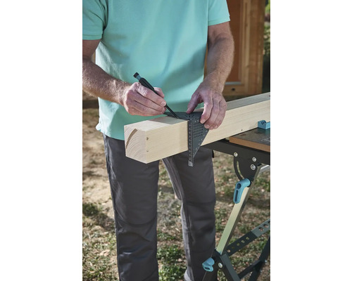 Remeselník kreslí značku na drevenej doske pomocou uholníka a ceruzky.