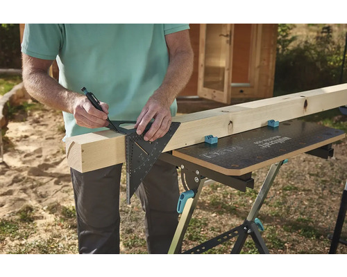 Osoba označuje kus dreva pomocou uholníka a ceruzky na pracovnom stole.