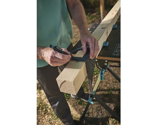 Osoba označuje kus dreva uholníkom na pracovnom stole.