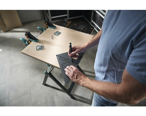 Muž pracuje s multifunkčným uholníkom na pracovnom stole a opracováva obrobok.