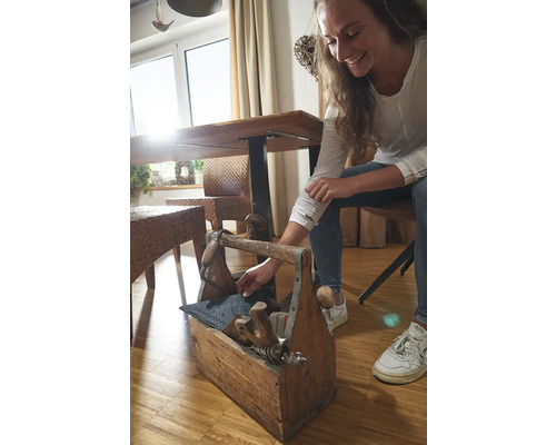 Žena siaha do drevenej debny na náradie s rôznym náradím