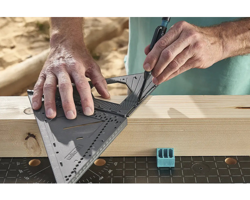 Osoba rysova čiaru na kuse dreva pomocou uholníka a ceruzky.