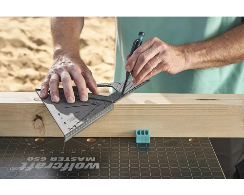 Osoba používa uholník na nakreslenie čiary na drevenú dosku.