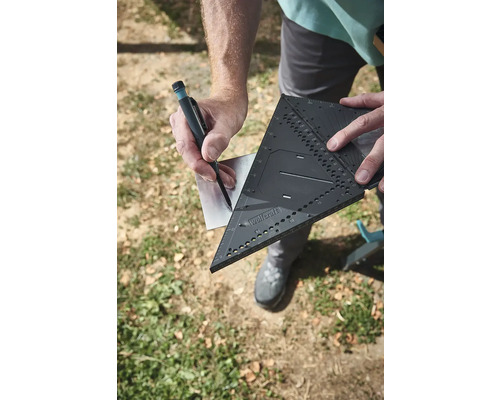 Remeselník značí kov pomocou tesárskeho uholníka a ceruzky.