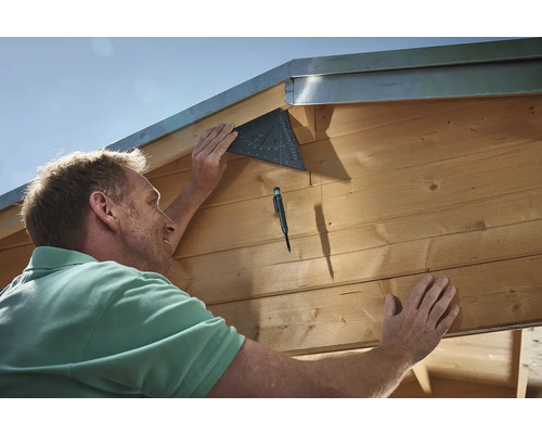 Remeselník pripevňuje uholník k drevenej budove.