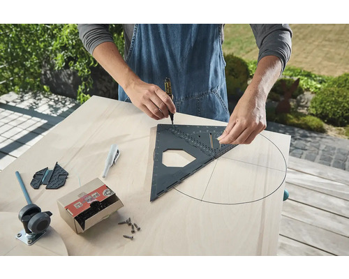 Osoba kreslí kruh na drevenú dosku pomocou stolárskeho uholníka a ceruzky. Náradie a skrutky sú pripravené.