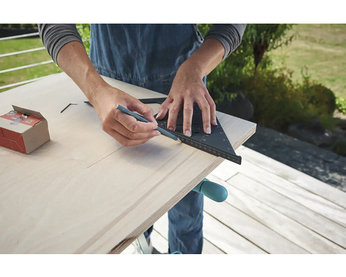 Osoba kreslí ceruzkou a uholníkom na drevo