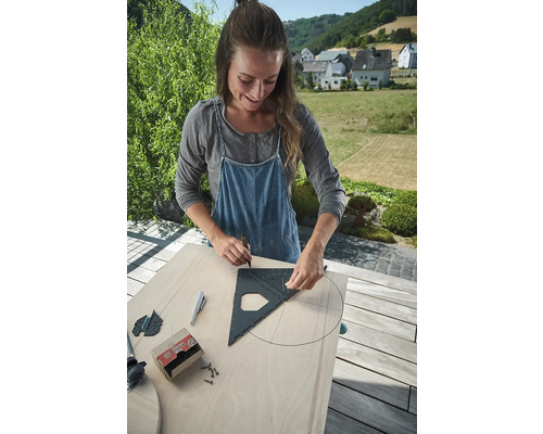 Žena kreslí kruh pomocou tesárskeho uholníka na drevenú dosku