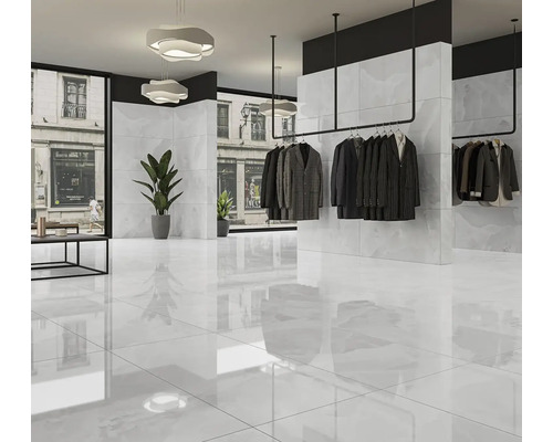 Svetlý predajný priestor s oblečením na vešiakoch a lesklou dlažbou.