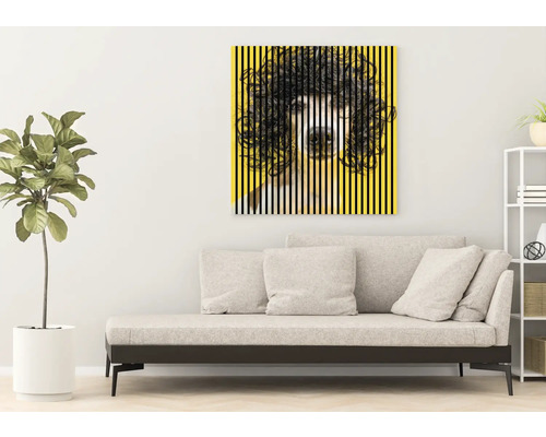 Obývacia izba s dennou posteľou a žltým zarámovaným obrazom s motívom psa.