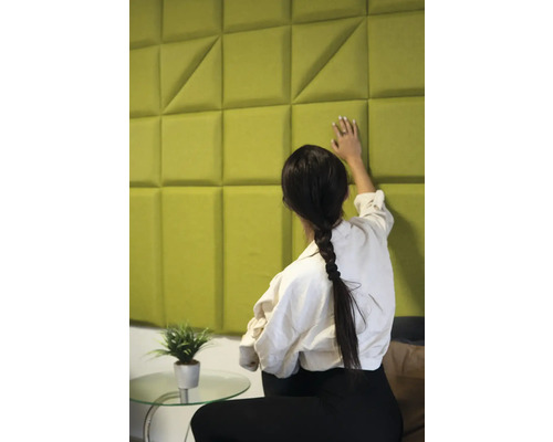 Žena sa dotýka akustického panela s geometrickým vzorom na stene