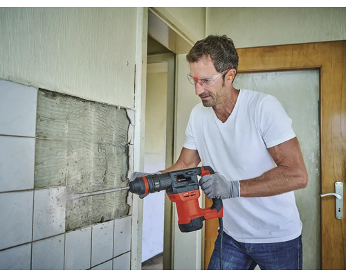 Muž odstraňuje dlaždice zbíjacím kladivom v miestnosti, ktorá si vyžaduje rekonštrukciu