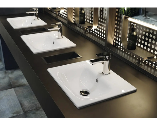 Tri biele umývadlá s batériami na tmavom povrchu