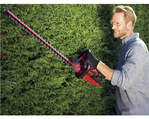 Muž strihá živý plot pomocou akumulátorových nožníc na živý plot