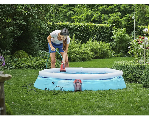 Žena používa ponorné čerpadlo na odstránenie vody z bazéna v záhrade.