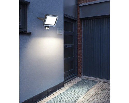 Vonkajšia fotografia osvetleného vonkajšieho LED svietidla s detektorom pohybu na stene domu