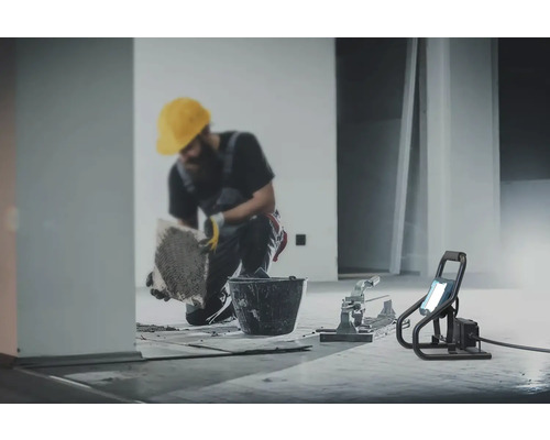 Remeselník kladie dlaždice s náradím a stavebným reflektorom