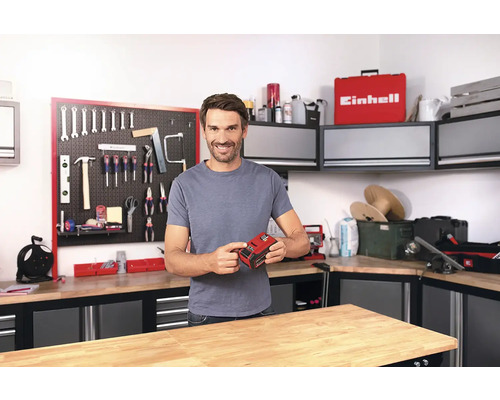 Muž drží akumulátor Einhell v dielni