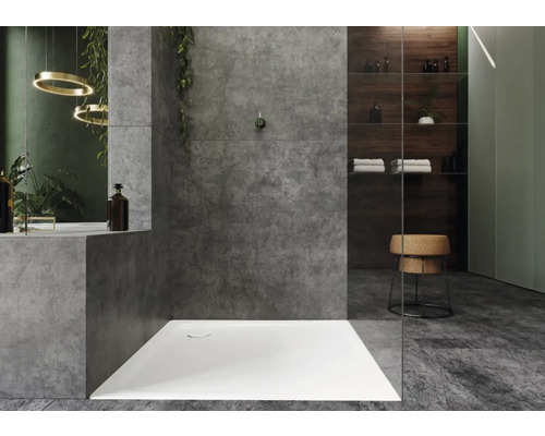 Moderný sprchovací kút so sivými stenami, sprchovou vaničkou a úložným priestorom