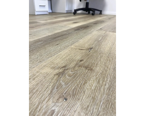 Detail svetlej laminátovej podlahy s dreveným vzhľadom v kancelárii.