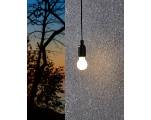 Závesná lampa so žiarovkou pred stenou