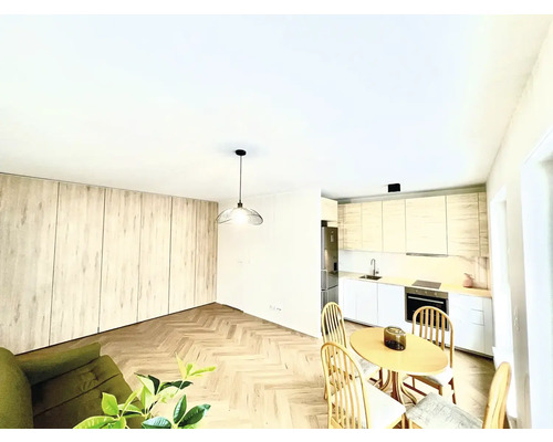 Svetlá obývacia izba s kuchyňou, jedálenským stolom a drevenou podlahou.