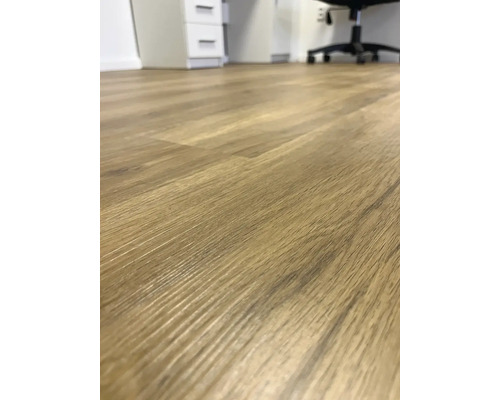 Detail svetlej laminátovej podlahy s drevenou štruktúrou v miestnosti.