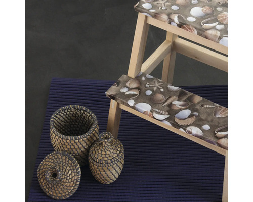 Scéna s drevenou stoličkou so vzorom mušlí, dvoma košíkmi a kobercom