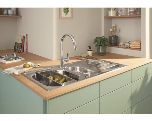 Nerezový kuchynský drez s odkvapkávačom a vodovodnou batériou vo svetlej kuchyni