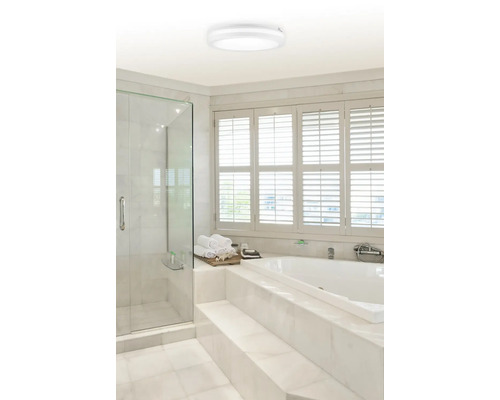 Moderná kúpeľňa so sprchovacím kútom, vaňou a okrúhlym stropným svietidlom.