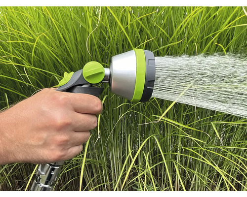 Ruka drží záhradnú striekaciu pištoľ, ktorá strieka vodu.