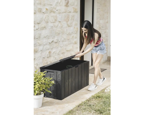 Žena otvára čierny záhradný box na vonkajšie uskladnenie