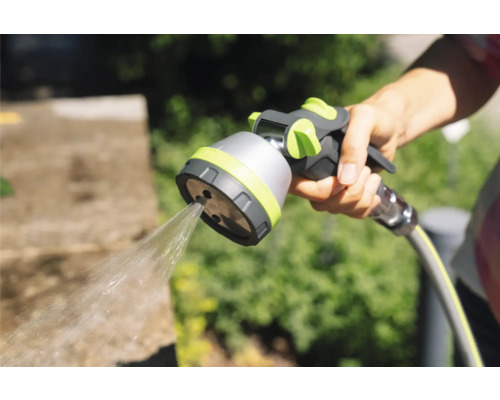 Ruka drží záhradnú hadicovú striekaciu pištoľ s prúdom vody.