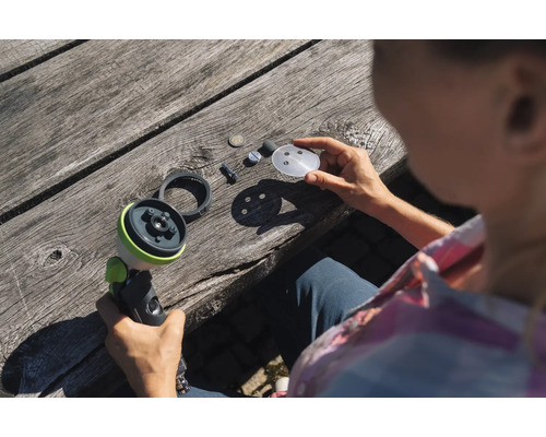 Žena demontuje záhradný postrekovač na drevenom stole