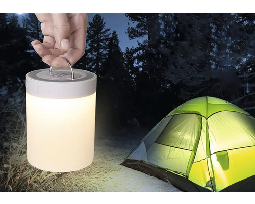 Scéna s rukou držiacou kempingovú lampu a stan vonku