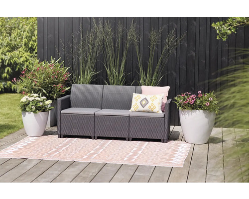 Sada záhradného nábytku s lavičkou, vankúšmi a kvetináčmi na terase