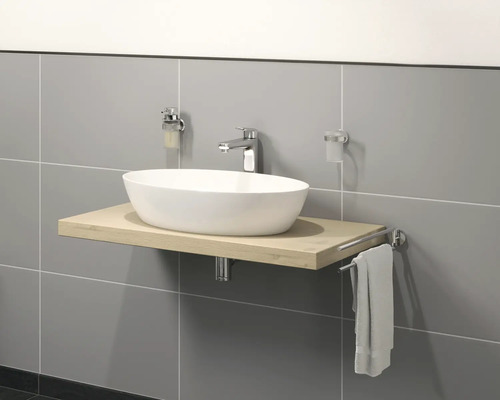 Umývadlo na drevenej doske s batériou, dávkovačom mydla, pohárom na zubné kefky a držiakom na uteráky pred sivou stenou